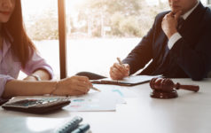Image of a business man supervising and secretary executing business plan. Consultant analyzing company annual financial report balance sheet statement working with documents graphs; visualizes an audit and consultant.