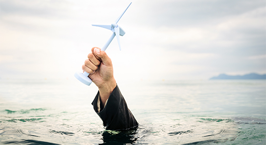 businessman holding a wind turbine above the water. concept for illustration the success - or failure - of off-shore wind power.