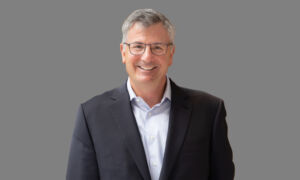 1000x600-Erik-Hirsch-Full-Portait_6X1A0631 (1) Headshot of Erik Hirsch, co-CEO of Hamilton Lane, in a dark jacket and light shirt against a gray background.