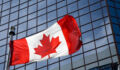 Canadian flag in front of modern building.