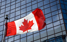 Canadian flag in front of modern building.