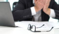 Stressed business man covering face with hands in office. Working over time or too much. Problem with failing business or confusion with crisis. Entrepreneur in bankruptcy.