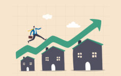 Housing price rising up, real estate or property growth concept, businessman running on rising green graph on house roof.