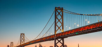 Classic panoramic view of San Francisco skyline with famous Oakland Bay Bridge illuminated in beautiful golden evening light at sunset in summer, San Francisco Bay Area, California, USA