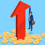 A giant red arrow lurches skyward as a man in a suit with a briefcase holds onwith one hand and dangles above the ground, which is strewn with dollar coins