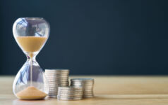 An hourglass next to a stack of coins