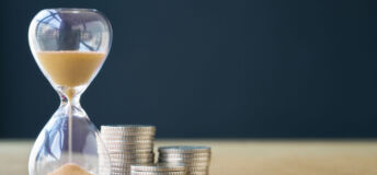 An hourglass next to a stack of coins