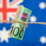 Australian regulator flags further surveillance of private funds market Close up of an Australian one hundred dollar bill tied in string. Australian flag in background.
