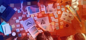 Marketing executives and graphic designers spread logo options and colour swatches over a table to decide on a rebrand