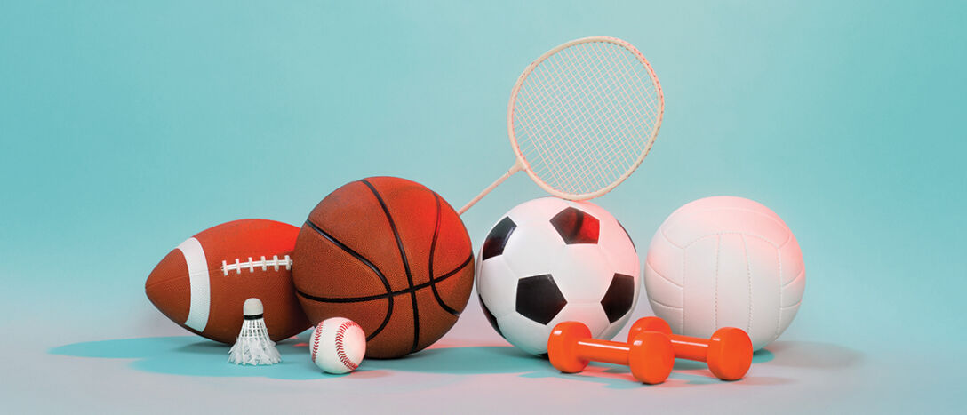 A pile of various sports equipment including a basketball, a shuttlecock and some weights