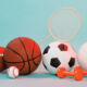 A pile of various sports equipment including a basketball, a shuttlecock and some weights
