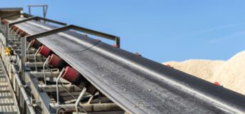Close-up shot of the conveyor belt in the concrete plant with transport rollers, visible metal stairs.