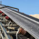 Close-up shot of the conveyor belt in the concrete plant with transport rollers, visible metal stairs.