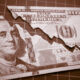 Image of a $100 bill torn in a decreasing line.