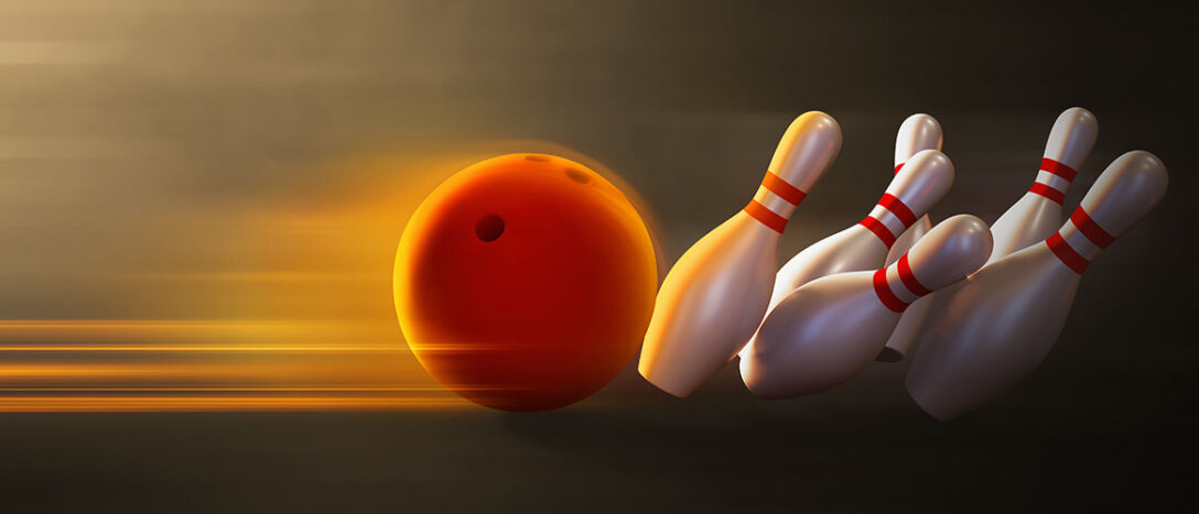 A bowling ball knocks over bowling pins