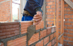 Worker building masonry house wall with bricks