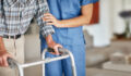 Shot of a woman assisting her elderly patient who's using a walker for support