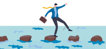 A businessman walks across stepping stones on water