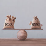 Risk and reward bags on a basic balance scale in equal position on wood table. risk management concept, depicts investors use a risk-reward ratio to compare the expected return of an investment