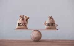 Risk and reward bags on a basic balance scale in equal position on wood table. risk management concept, depicts investors use a risk-reward ratio to compare the expected return of an investment