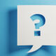 question mark cut out of card on a blue blackground
