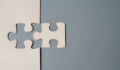 Two puzzle pieces connecting, one white and one grey, on a contrasting background