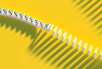 A line of dominoes begins to cascade over a yello floor