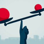 Image of a hand balancing red balls on a scale.